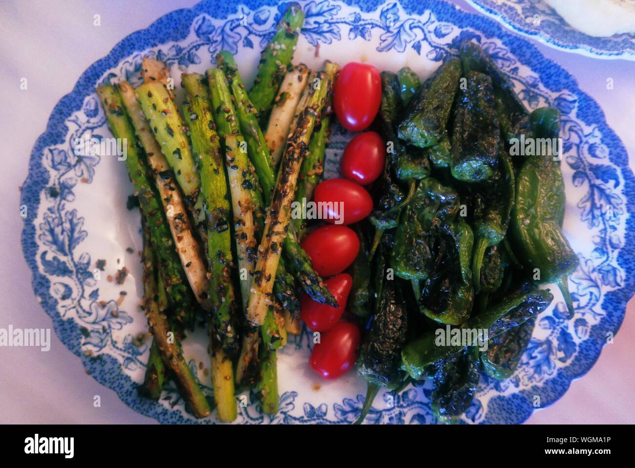Close-up Of Grilled Asparagus With Cherry Tomato And Green Chili Pepper In Plate Stock Photo