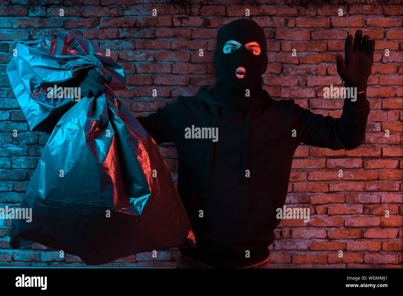 surprised thief hold the hands up and get illuminated from the police lights Stock Photo