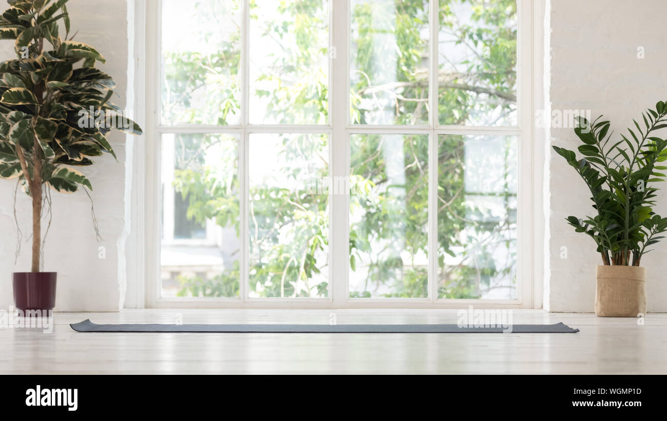 Empty yoga studio interior with windows and unrolled mat Stock Photo