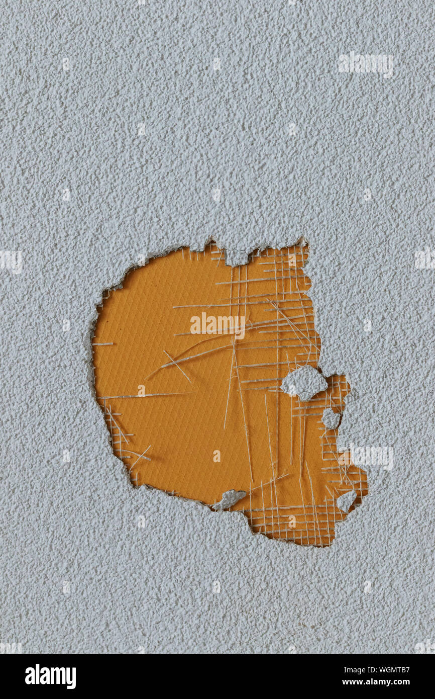 hole in the plaster wall covered by yellow surface Stock Photo