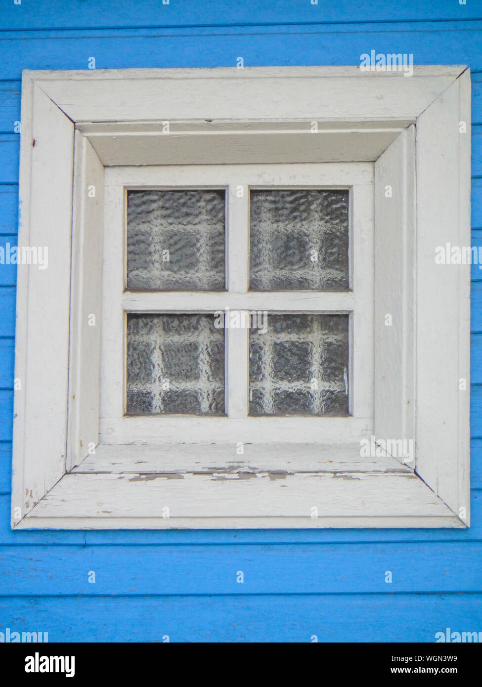 A white wooden window with a lattice and a guipure curtain against the background of a blue painted wooden wall - photo. Background. Architecture element Stock Photo