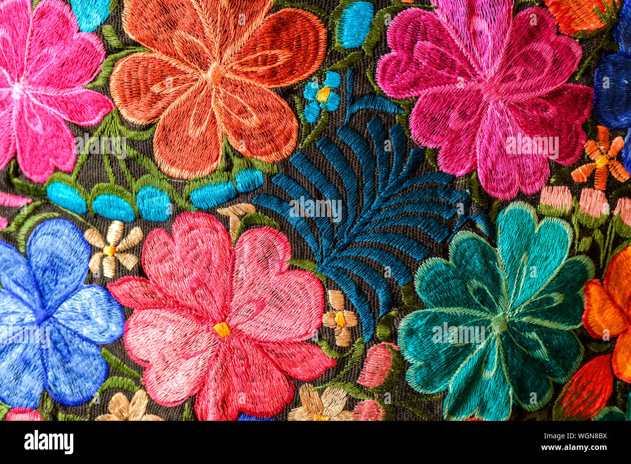 Background of hand-embroidered flowers on a fabric with colored threads. Stock Photo