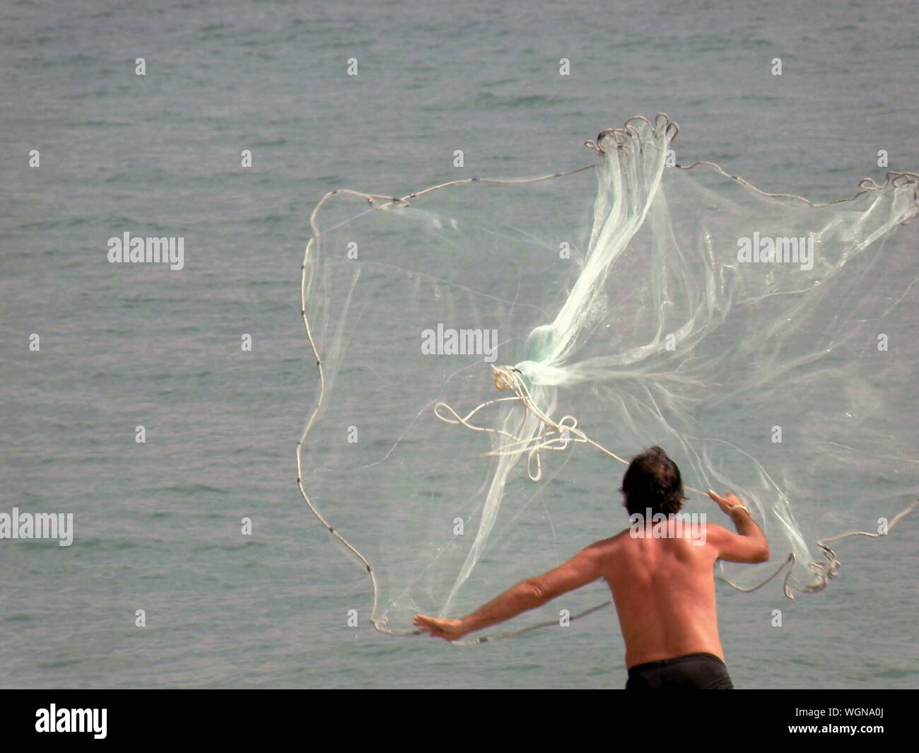 Man Throwing Fishing Net Into Water High Resolution Stock Photography