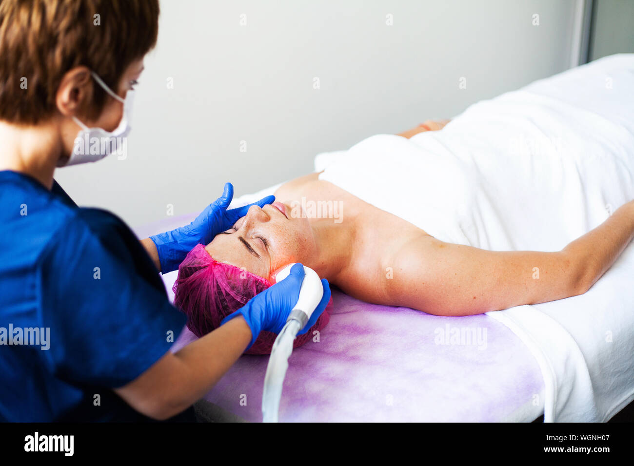 Woman getting LPG hardware massage at the beauty clinic. Professional beautician working. Stock Photo
