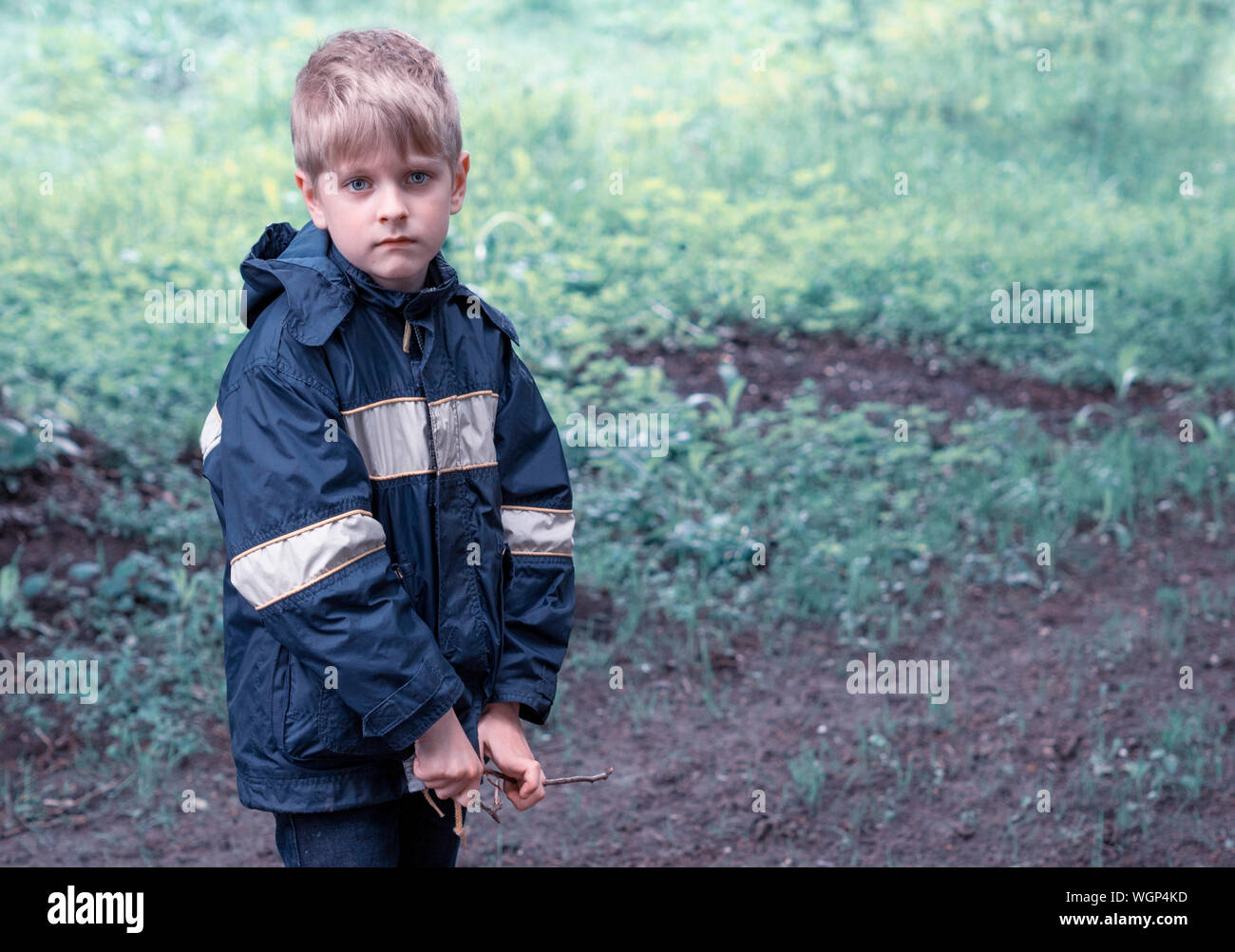 Portrait Of Boy Wearing Raincoat In Forest Stock Photo