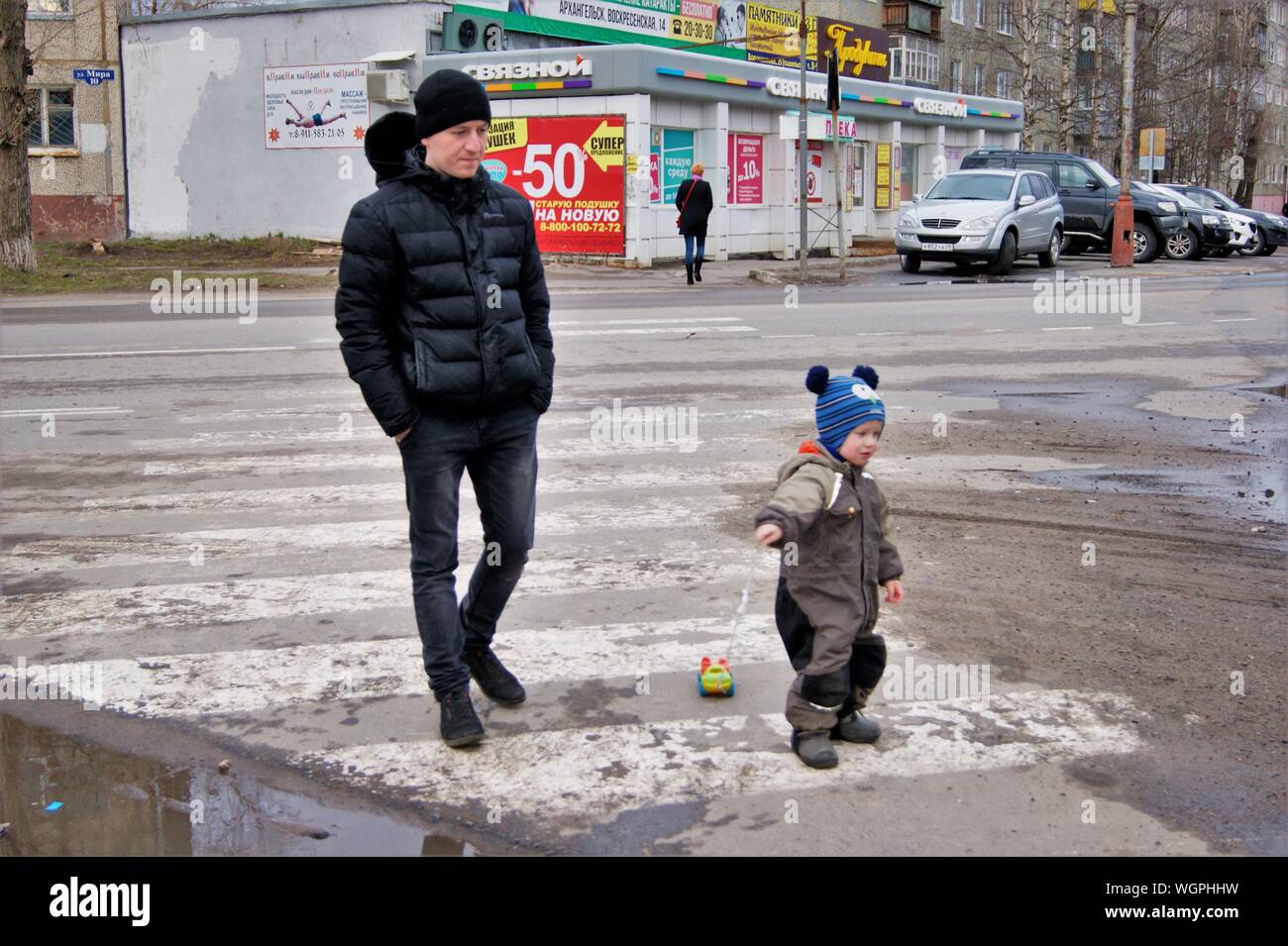 Novodvinsk, Arkhangelsk - Russia, April 2019 - Spring in a provincial town, father walks with a baby who is rolling a typewriter on a string Stock Photo