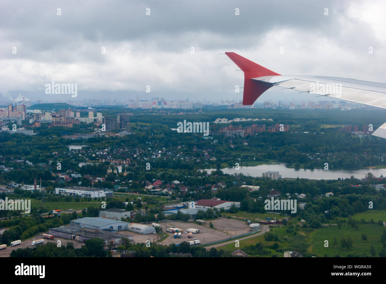Earth in the porthole under the wing of an airplane. Flying in the fog over cities, rivers, forests. Airplanes, flights, passengers, landscapes, observation Stock Photo