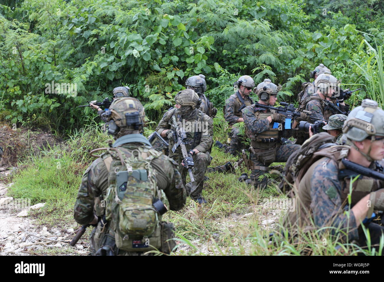 Operators with Special Operations Command Australia join U.S. Marines with 3rd Reconnaissance Battalion, 3rd Marine Division, during a training evolution as part of exercise HYDRACRAB in Santa Rita, Guam, Aug. 26, 2019. HYDRACRAB is a multilateral exercise conducted by U.S. Marines and Sailors with military service members from Australia, Canada, and New Zealand. The purpose of this exercise is to prepare the participating Explosive Ordnance Disposal forces to operate as an integrated, capable, and effective allied force ready to operate in a changing and complex maritime environment throughou Stock Photo