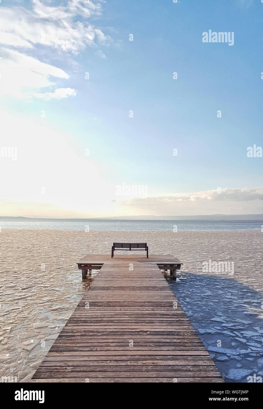 Pier At Beach Against Sky On Sunny Day During Winter Stock Photo