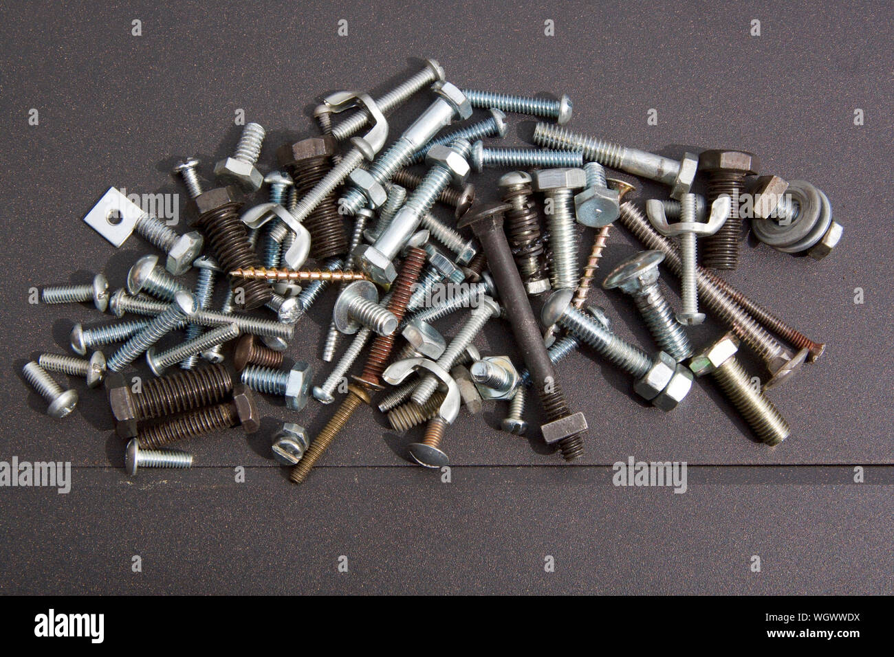 A collection of small metal bolts with a mix of nuts and an occasional screw. Stock Photo
