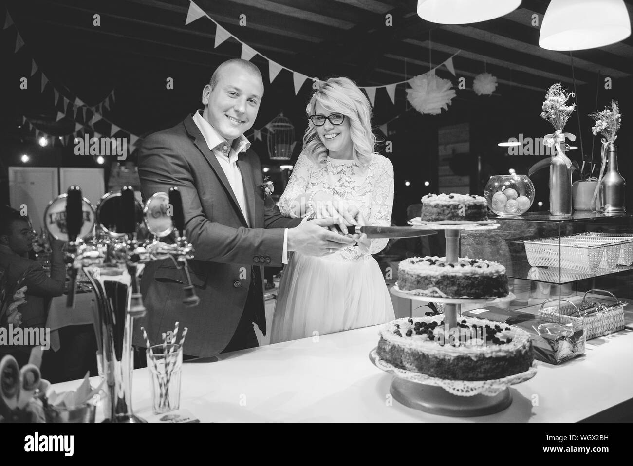 Portrait Of Newlywed Young Couple Cutting Cake During Wedding Reception Stock Photo Alamy
