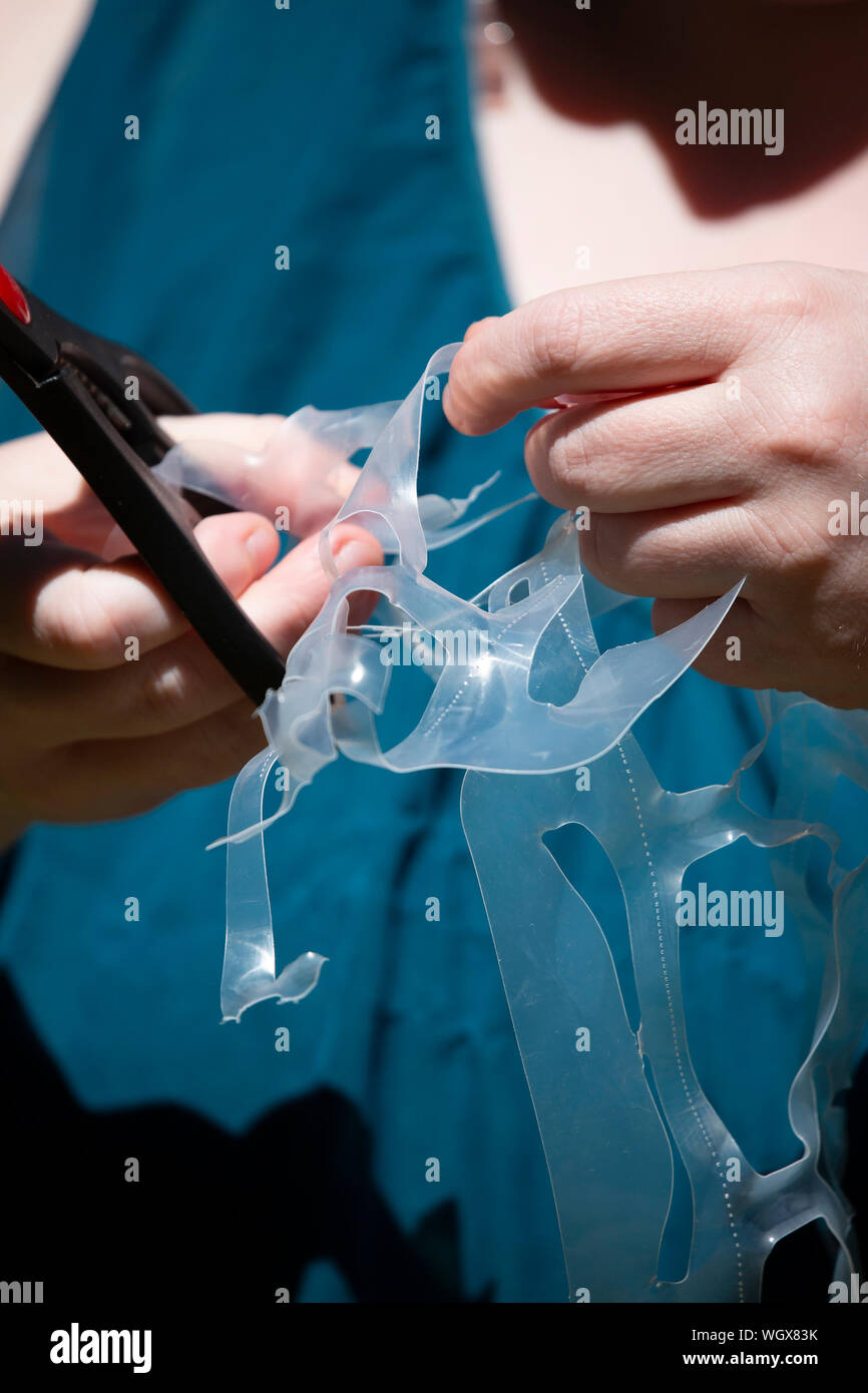 Woman cutting plastic rings before throwing them away to prevent them