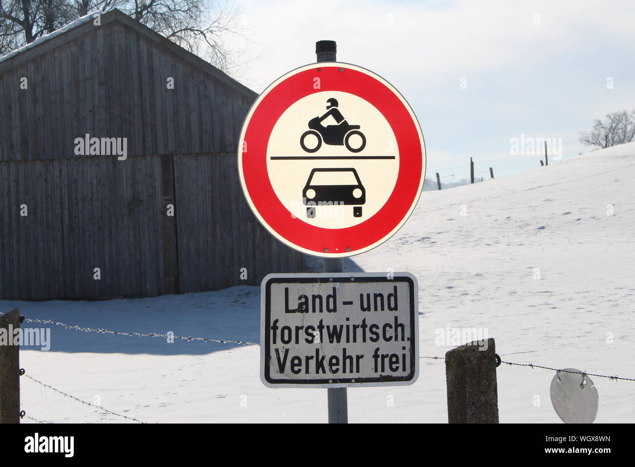 Sign Board By Fence Against Log Cabin On Snow Covered Field Stock