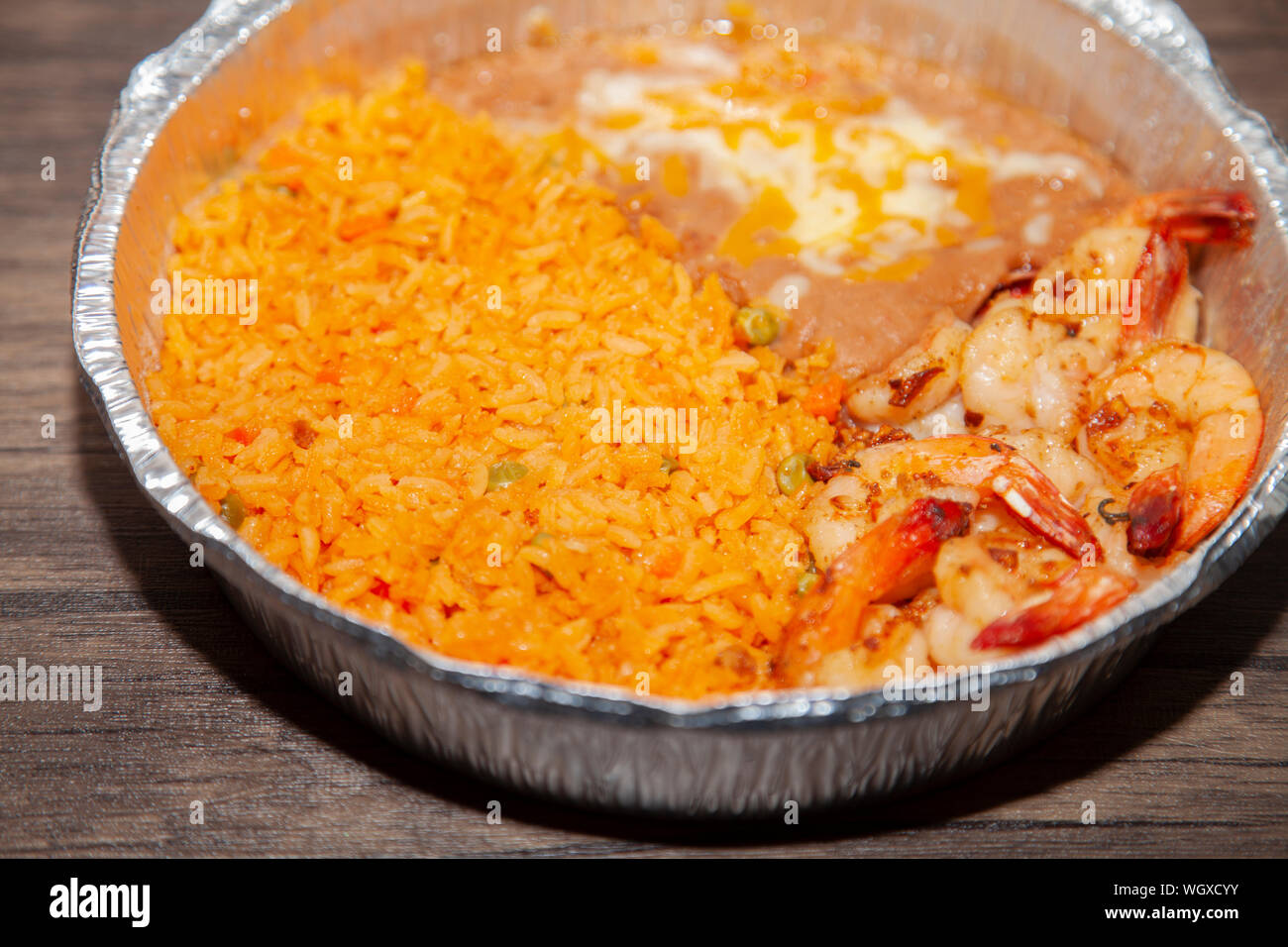 Grilled shrimp, fried rice, and refried beans in a baking tin Stock