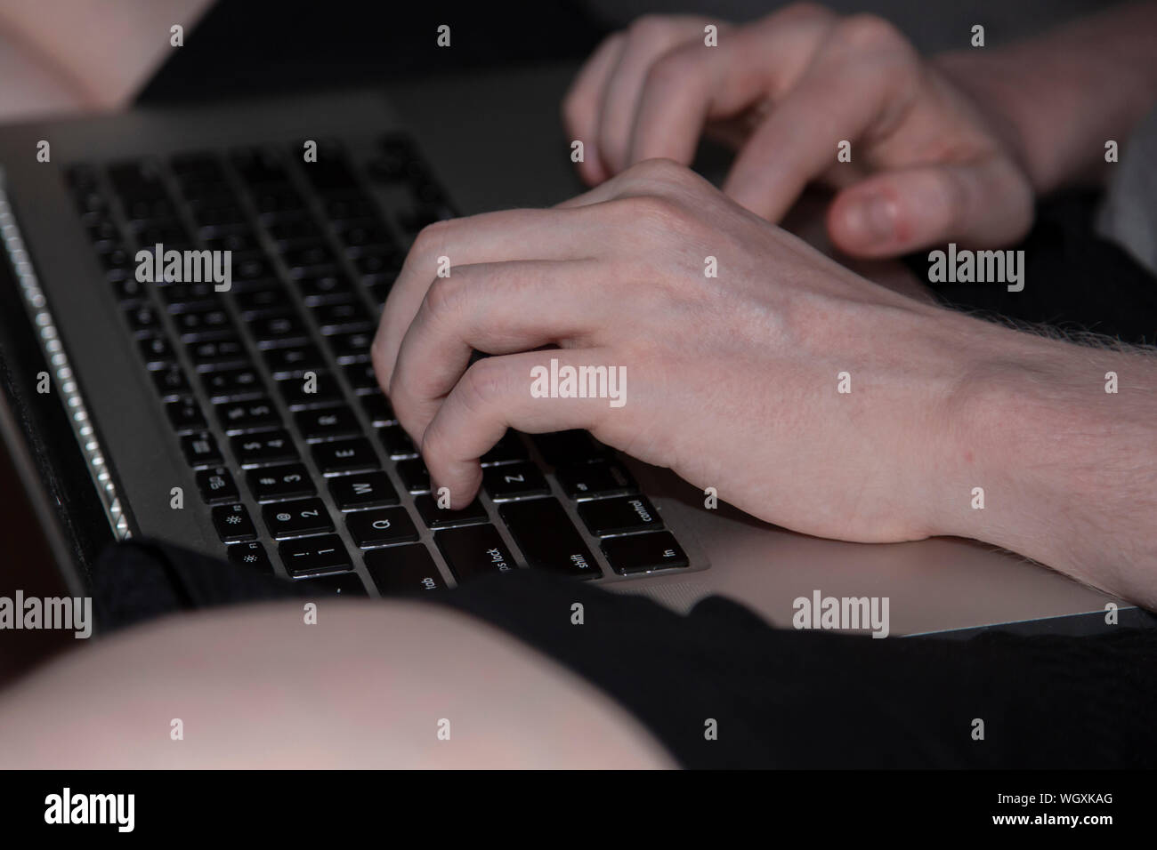 Man typing on a black and silver laptop keyboard Stock Photo