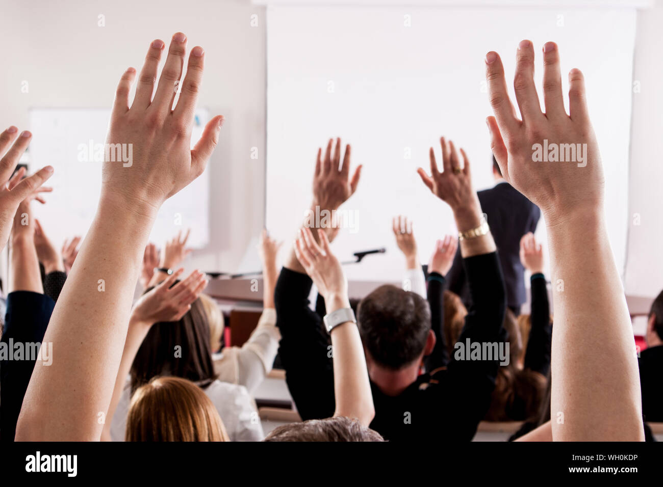 People With Arms Raised In Lecture Hall During Seminar Stock Photo