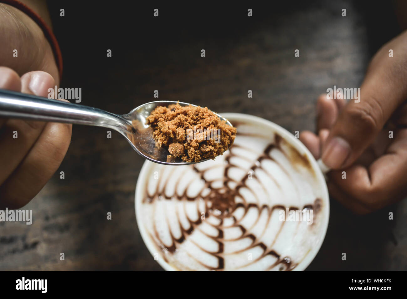 Cropped Hands On Person Adding Brown Sugar In Coffee At Table Stock Photo