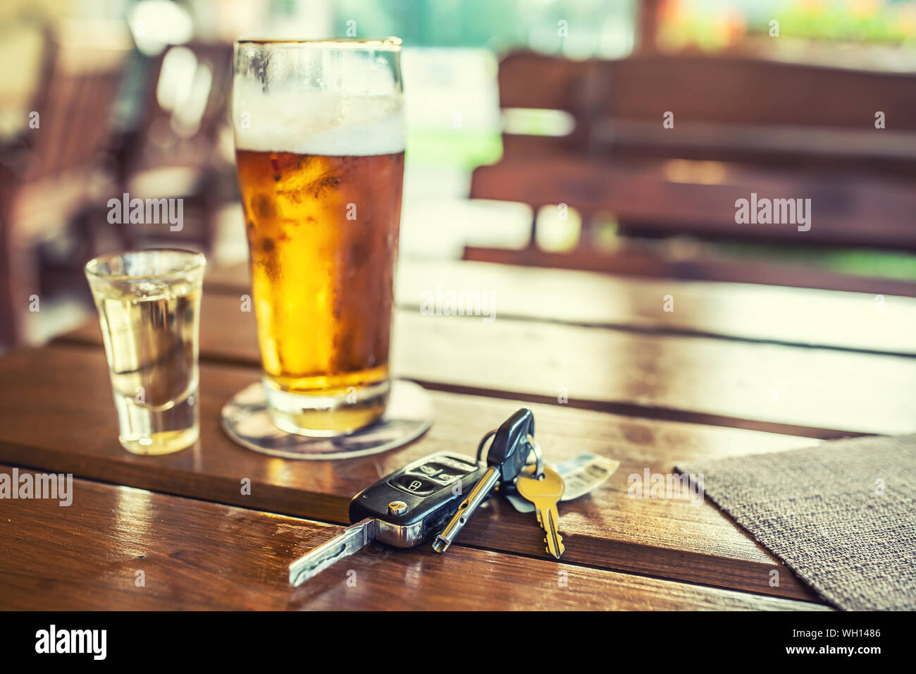 Car keys and glass of beer or distillate alcohol on table in pub or restaurant Stock Photo