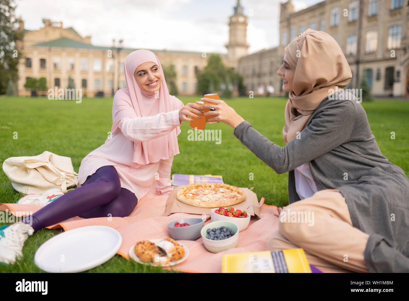 Cheerful muslim students enjoying pizza time outside Stock Photo