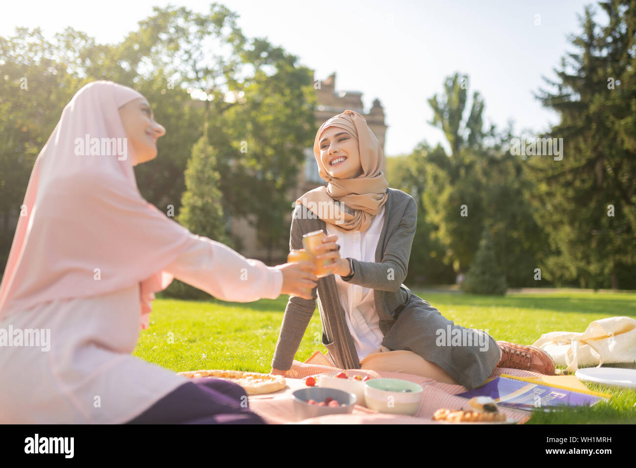 Muslim students drinking soda while having lunch outside Stock Photo