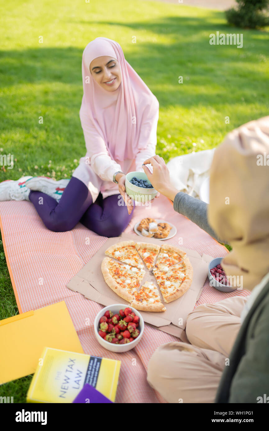 Women in hijabs eating pizza and fruits after studying Stock Photo