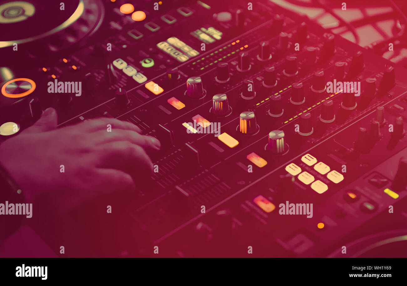 Concert dj mixing music on night club party in bright red stage lights.Professional disc jockey