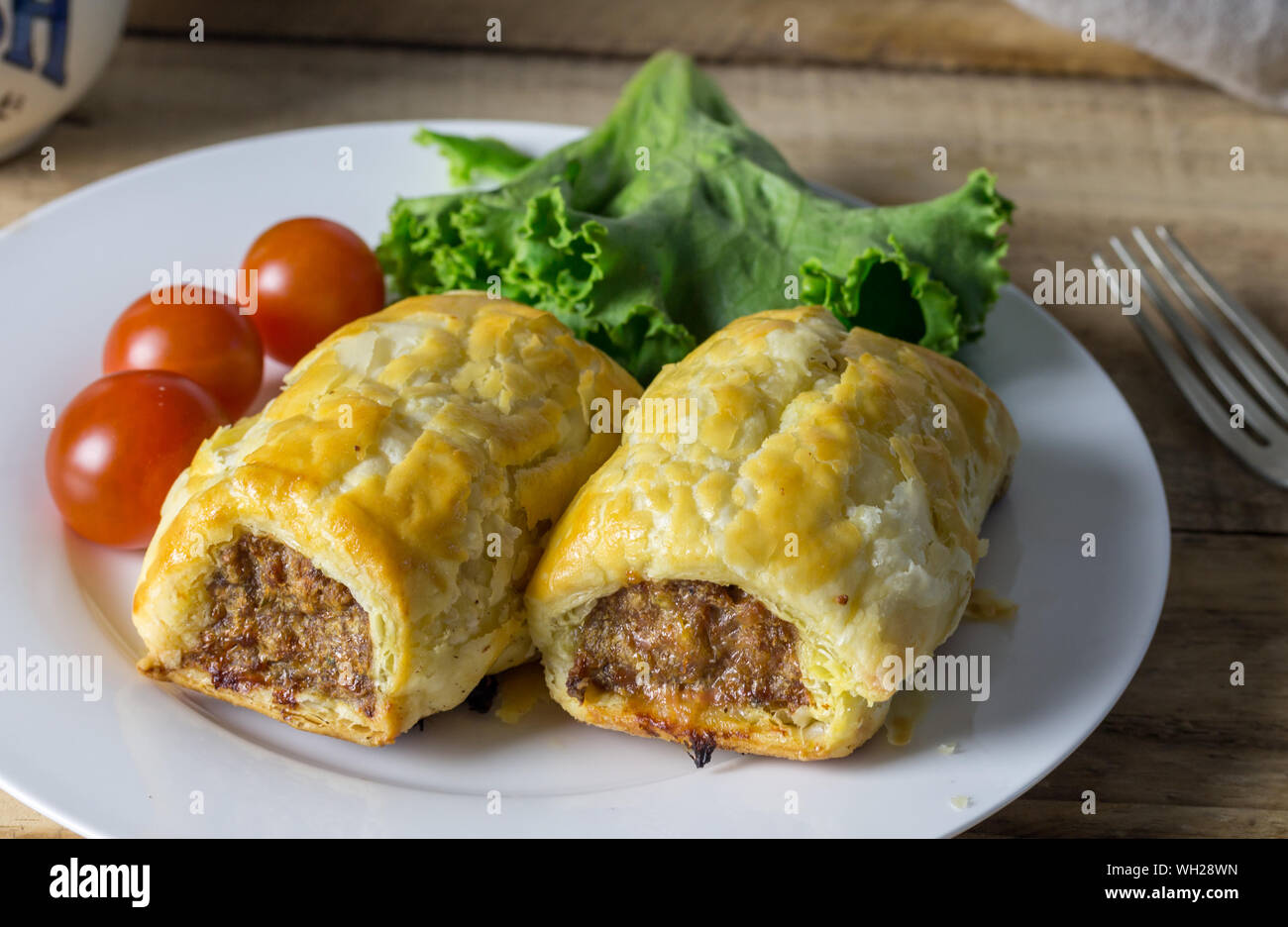Sausage rolls with lettuce and tomato - dinner snack Stock Photo