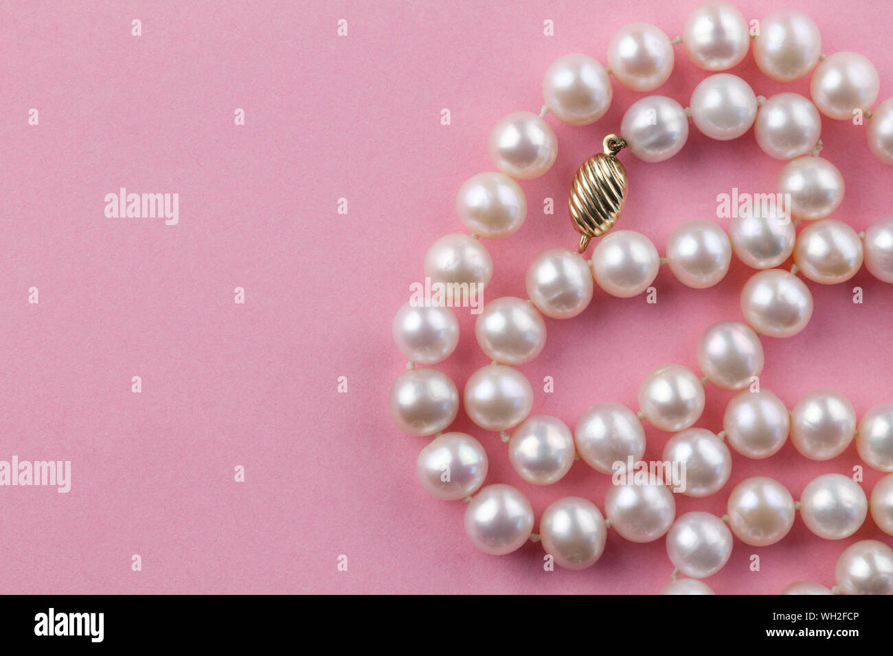 Pink string with pink red blue hearts beads on white background