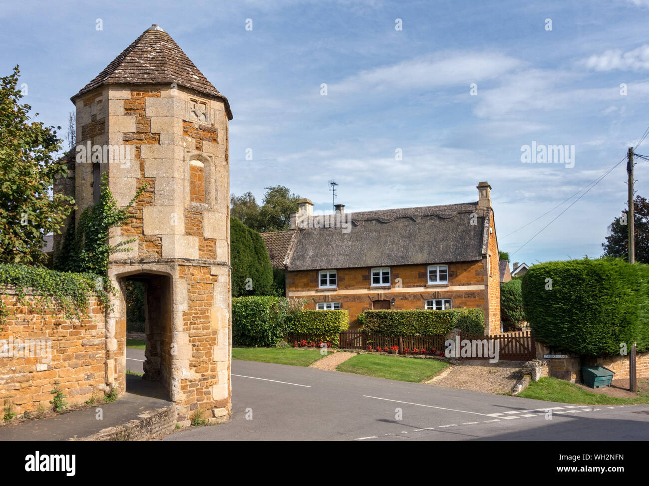 C15 Bishops Eye watchtower gazebo with passageway and pretty stone cottage with thatched roof, Church Street, Lyddington, Rutland, England, UK Stock Photo