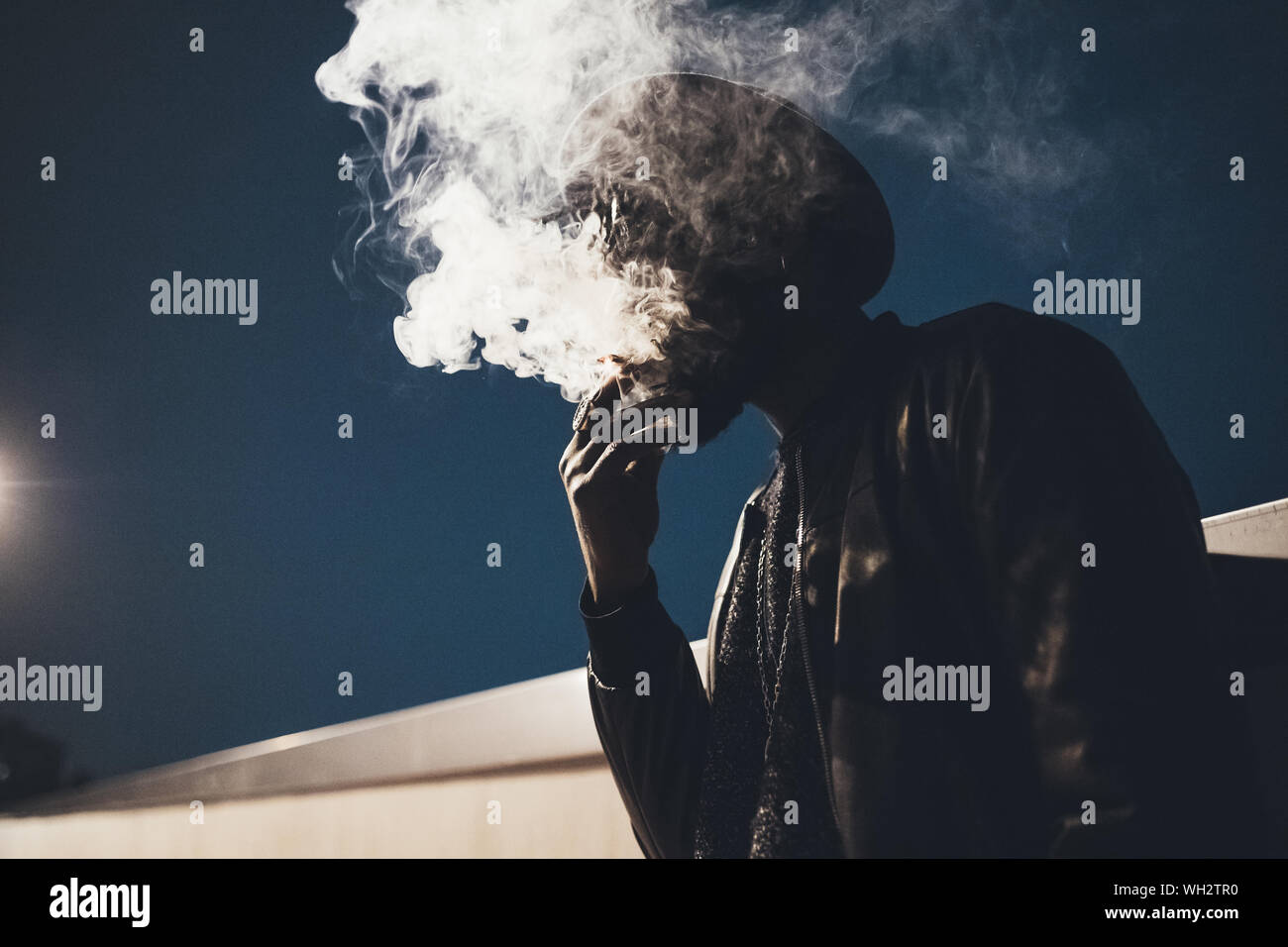portrait of young black man standing outdoor smoking cigarette youth