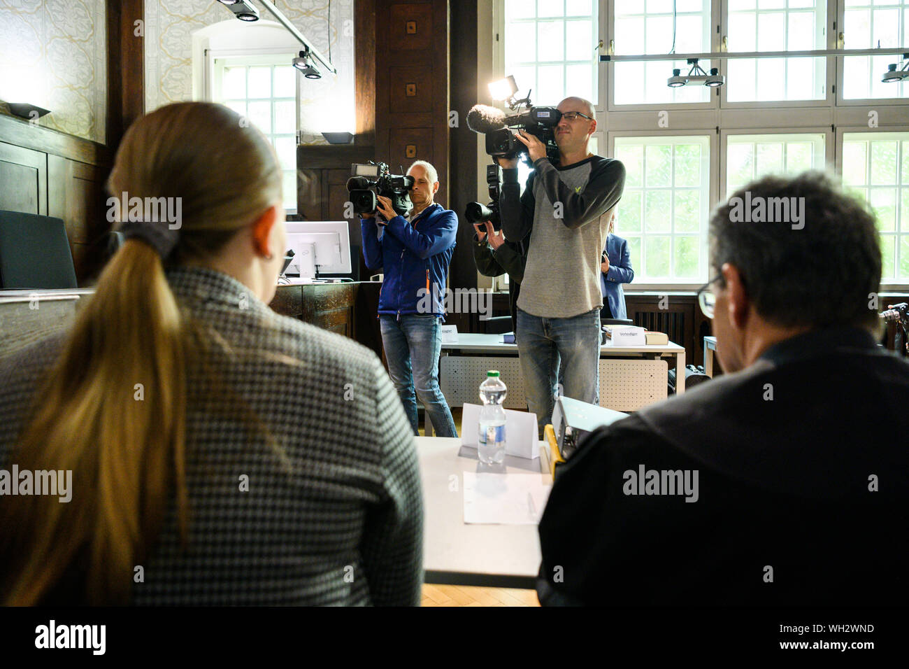02 September 2019, Lower Saxony, Emden: A joint plaintiff (l) sits next to her lawyer in the courtroom shortly before the trial begins and is filmed by representatives of the press. The tragic case had caused consternation in August 2016, when two boats, each with four young occupants, had driven together on the way back from the harbour festival in Barßel. A skipper is said to have been drunk with 1.89 per mille and to have driven too fast. After years of wrangling over jurisdiction, the Federal Supreme Court referred the case to Emden. Seven witnesses have been summoned for the sole day of t Stock Photo