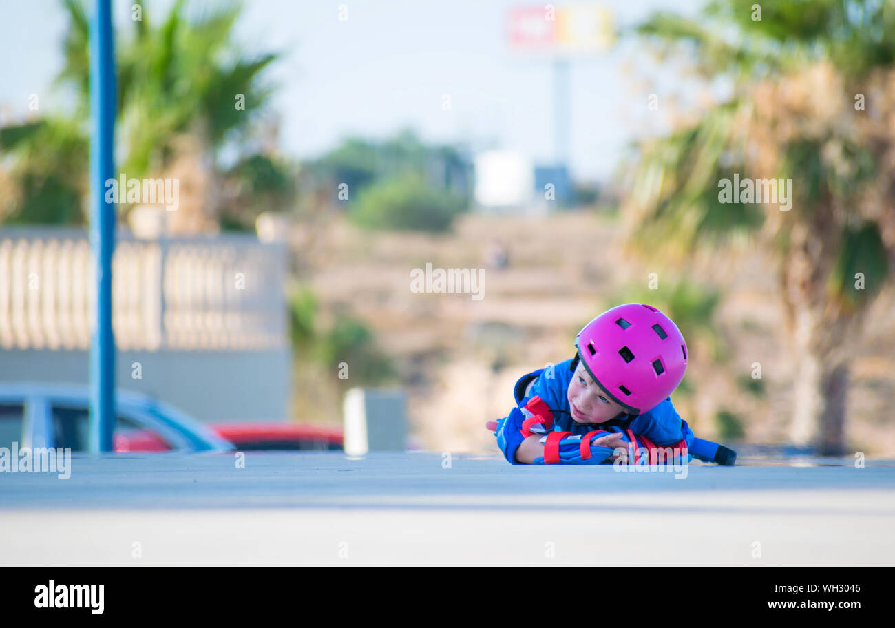 Murcia, Spain, July 17, 2019: adorable preschooler weepy as her rollerblades made her fall. On a city background. Initiation classes to rollerblading. Stock Photo
