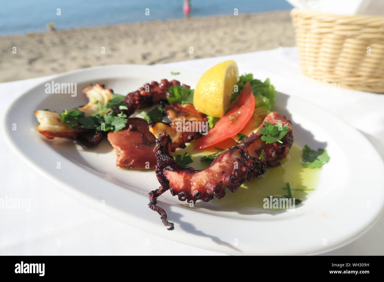 Grilled Octopus And Lemon In Plate On Table At Beach Stock Photo