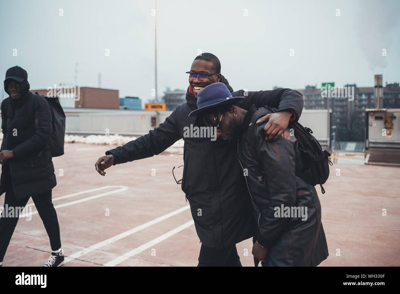 Man Interaction three young african men outdoor together in the street hugging having ...