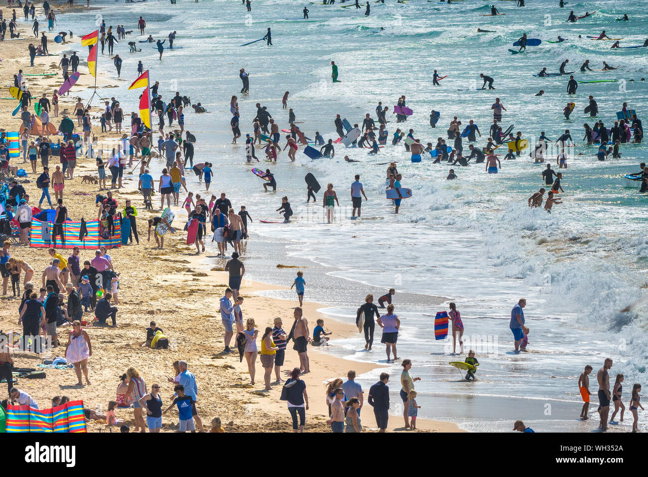 Holidaymakers enjoying themselves on a busy and crowded Fistral Beach in Newquay in Cornwall. Stock Photo