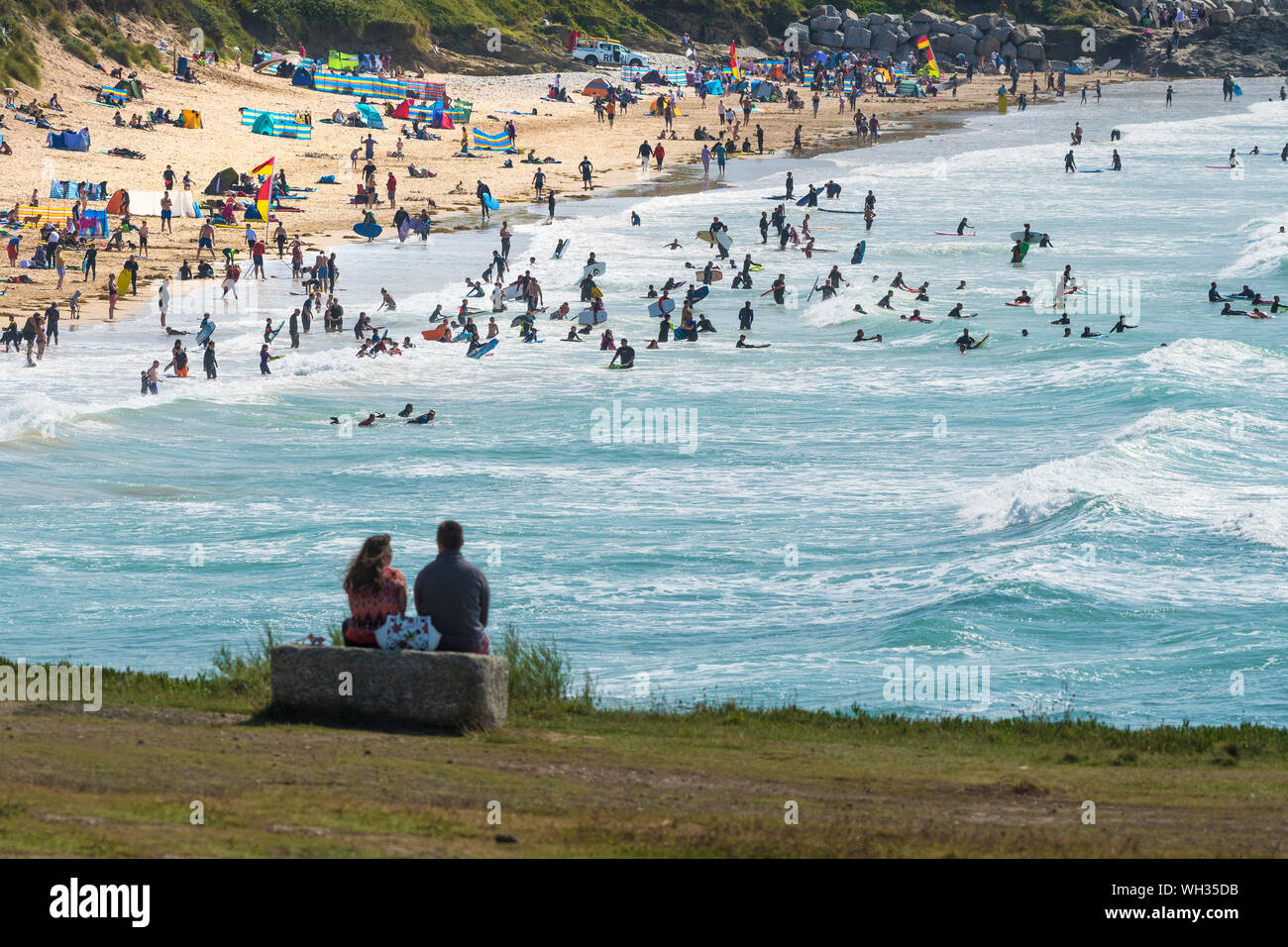 Holidaymakers on a staycation holiday on a sunny Fistral Beach and in the sea in Newquay in Cornwall. Stock Photo