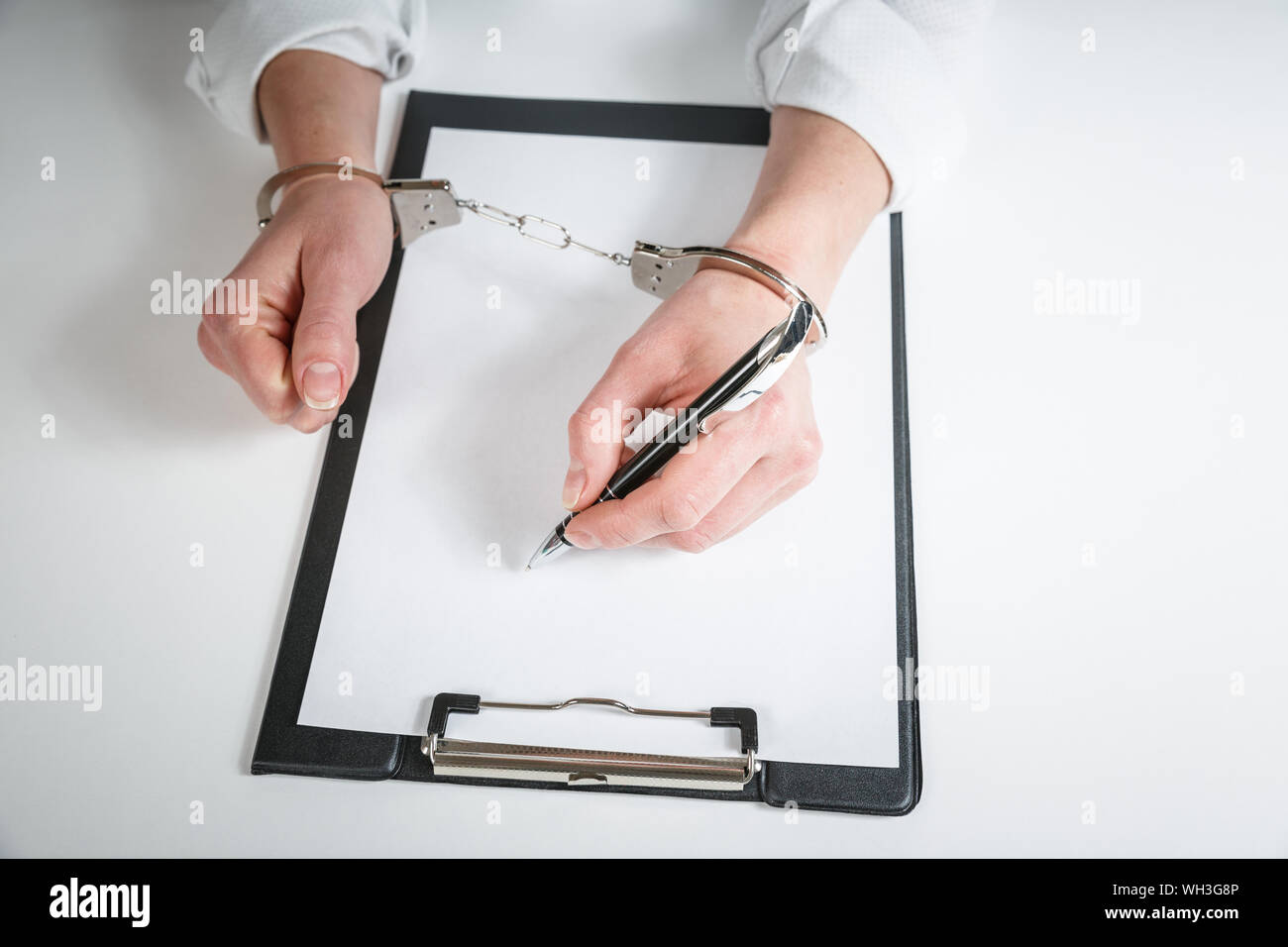 Female hands in handcuffs fill out police report recognition. Stock Photo