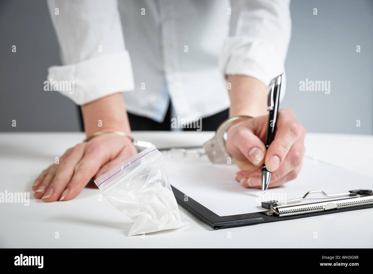 Female hands in handcuffs fill out police report recognition. Stock Photo