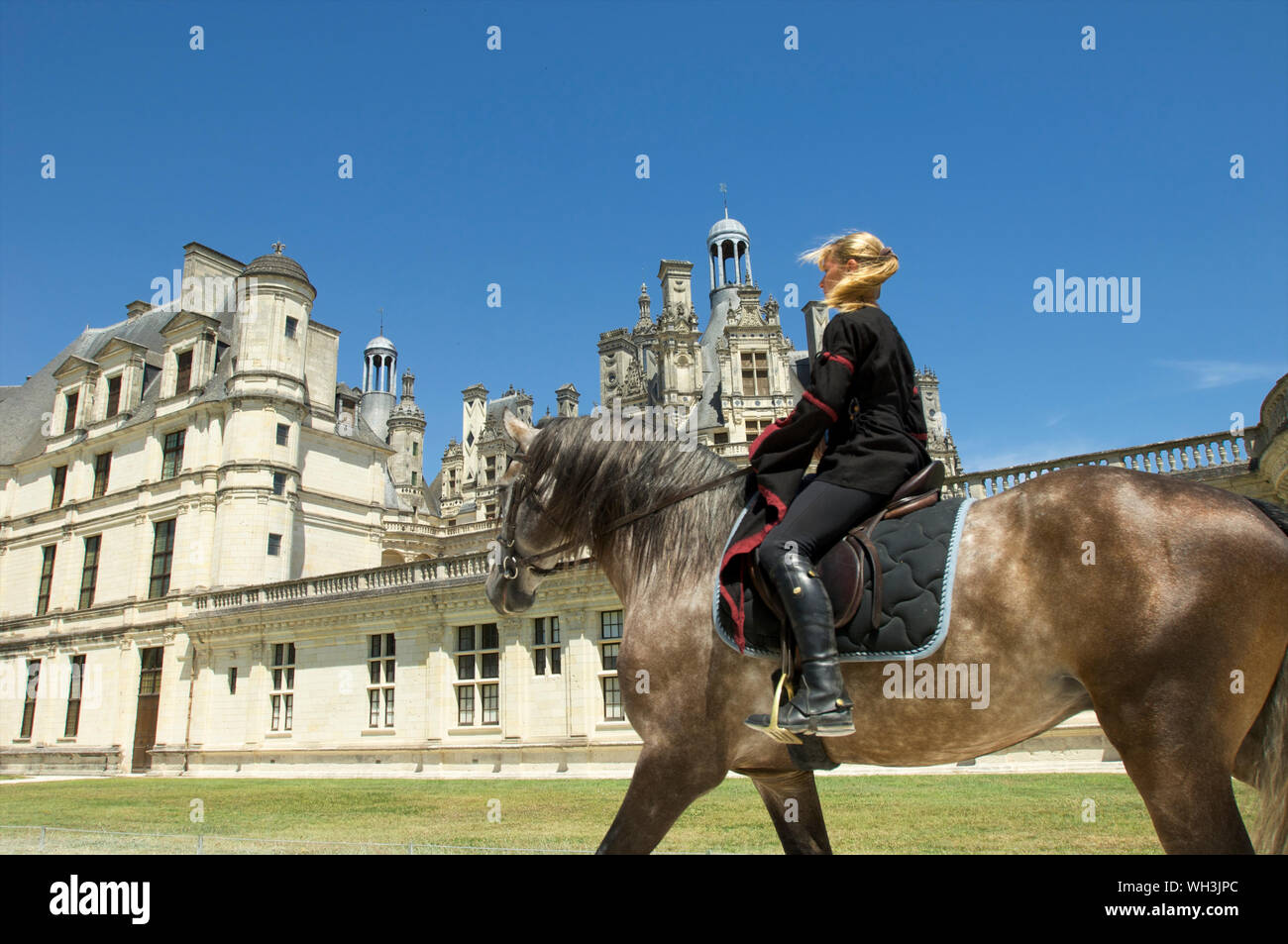 Girl on a horse passing the Chambord castle in Blois in Loire Valley, France Stock Photo