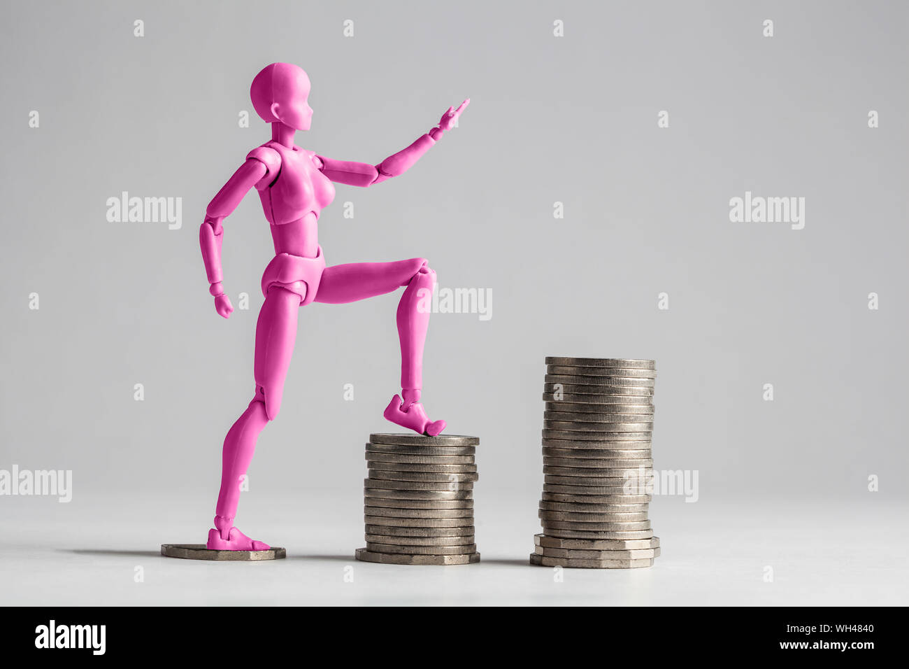 Magenta Figurine On Stacked Coins Against White Background Stock Photo