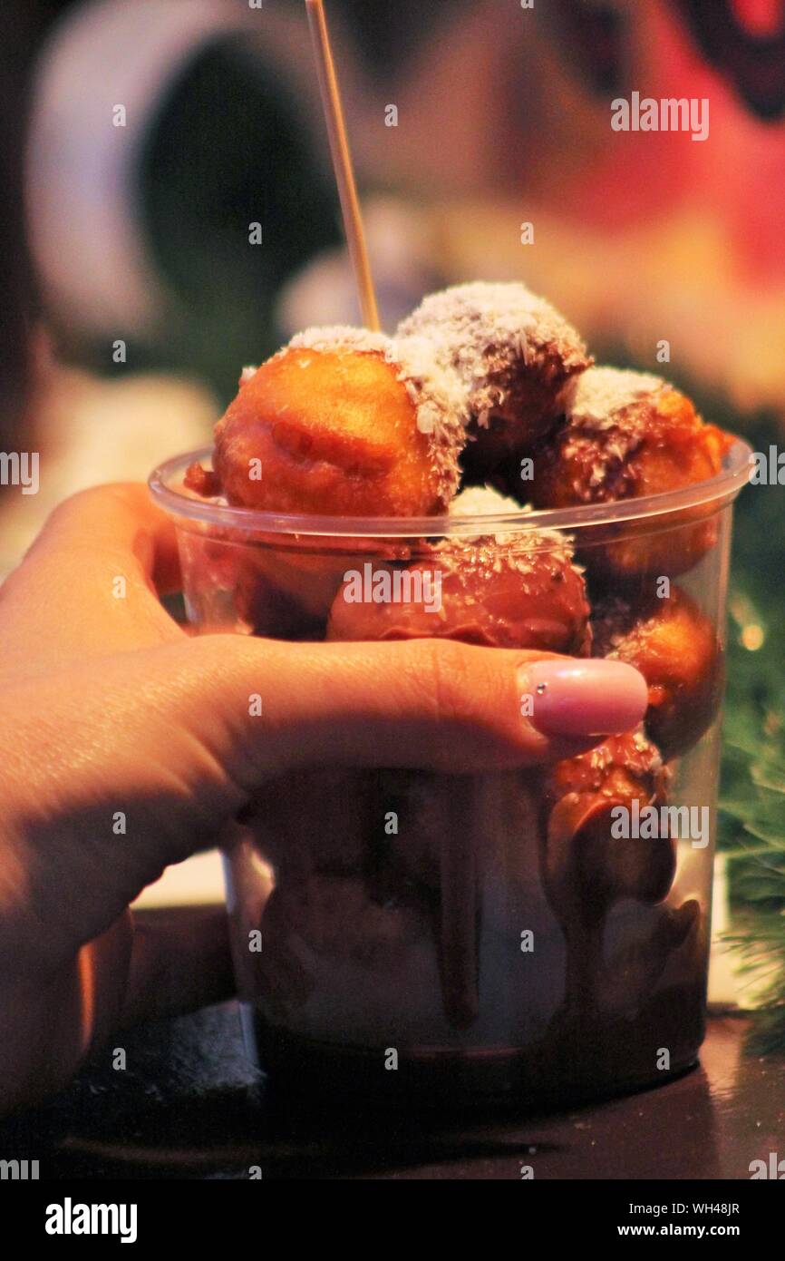 Cropped Hand Of Woman Holding Fritter In Disposable Cup Stock Photo