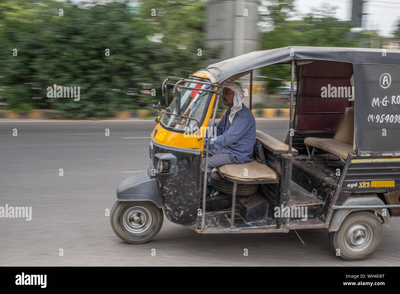 A rickshaw speeding down a road in Gurgaon, India. Stock Photo