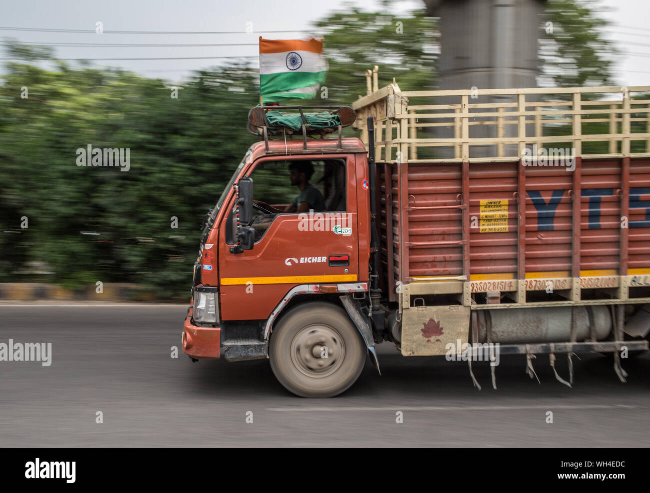 A truck with a Indian flag speeding down a road in Gurgaon, India. Stock Photo