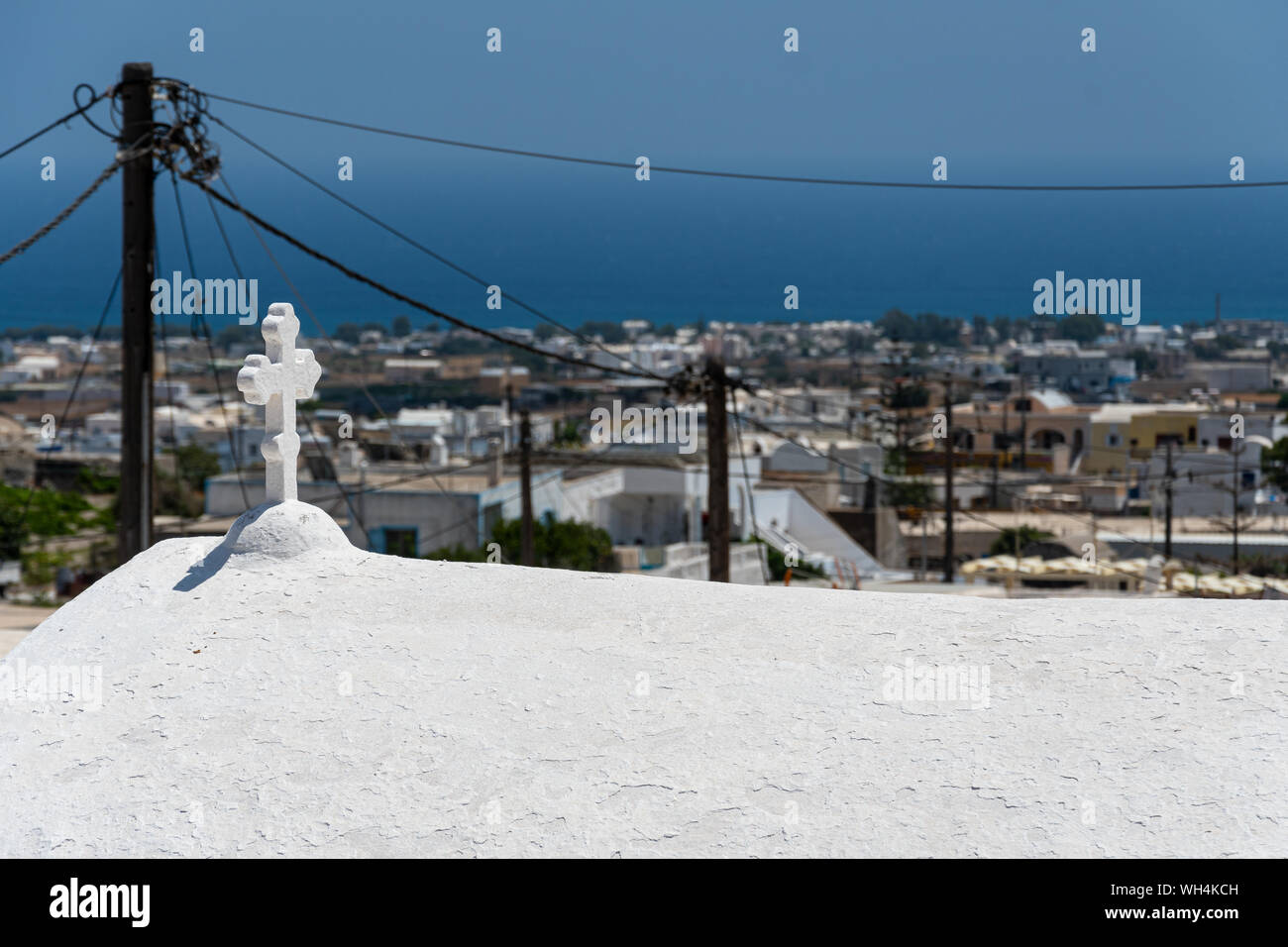 The cross and arched roof of a Greek orthodox church looms over Emporio ...