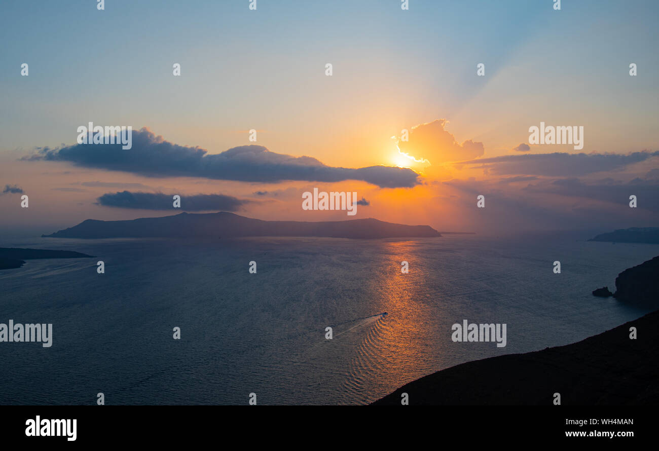 The sun setting over the islands of Santorini in the Aegean sea Stock Photo