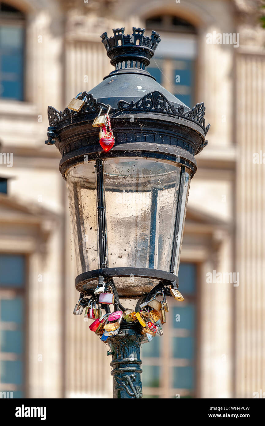 Bundle of padlocks and a red heart key ring locked onto a lamppost at ‘Pont des Arts’ pedestrian bridge in Paris. Stock Photo