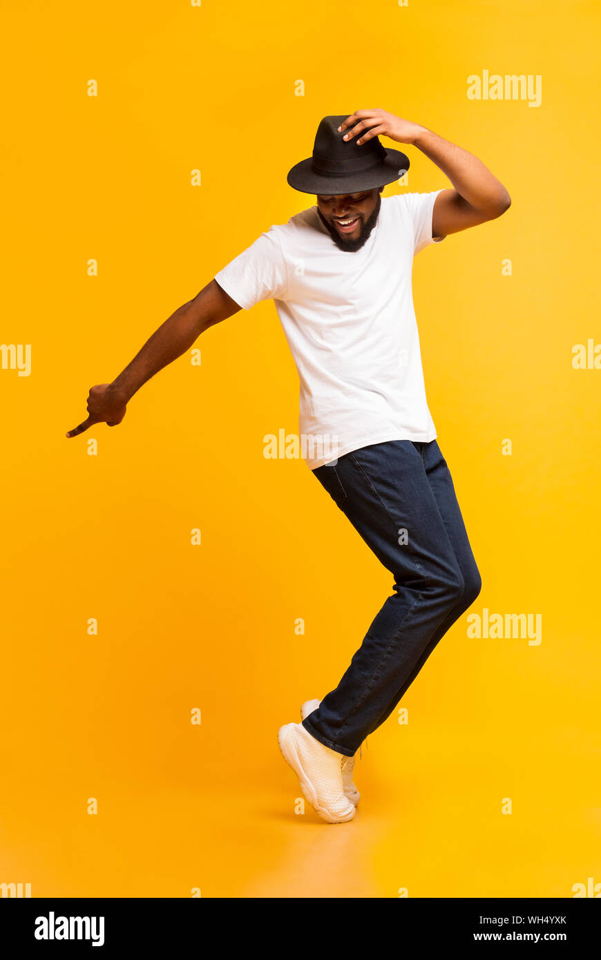 Young cheerful man dancing on tiptoes on yellow studio background Stock Photo