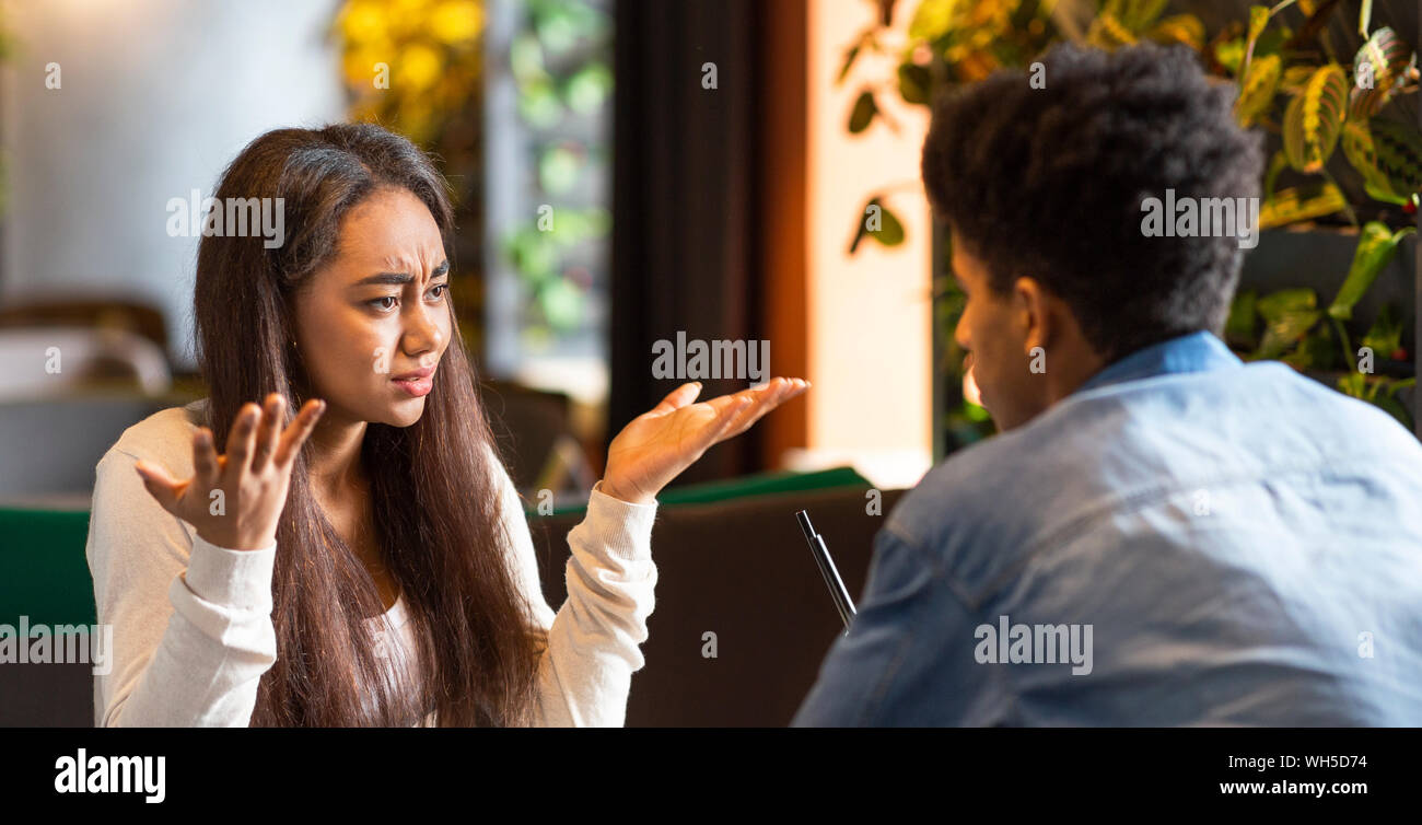 Furious young girl desperately looking at afro guy Stock Photo