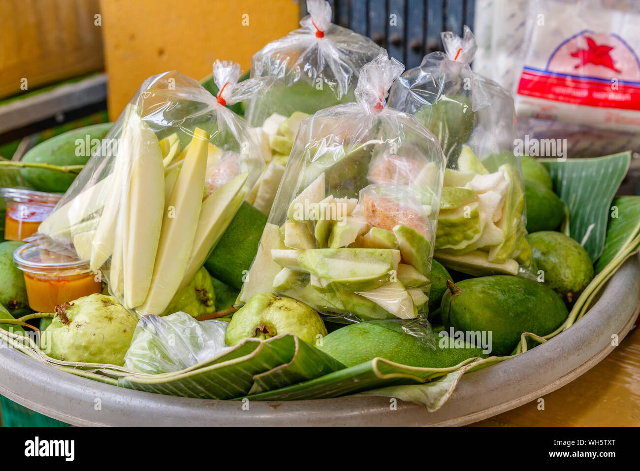 Peeled and sliced green mango with salt and chili pepper, popular Thai street food. Bangkok, Thailand. Stock Photo