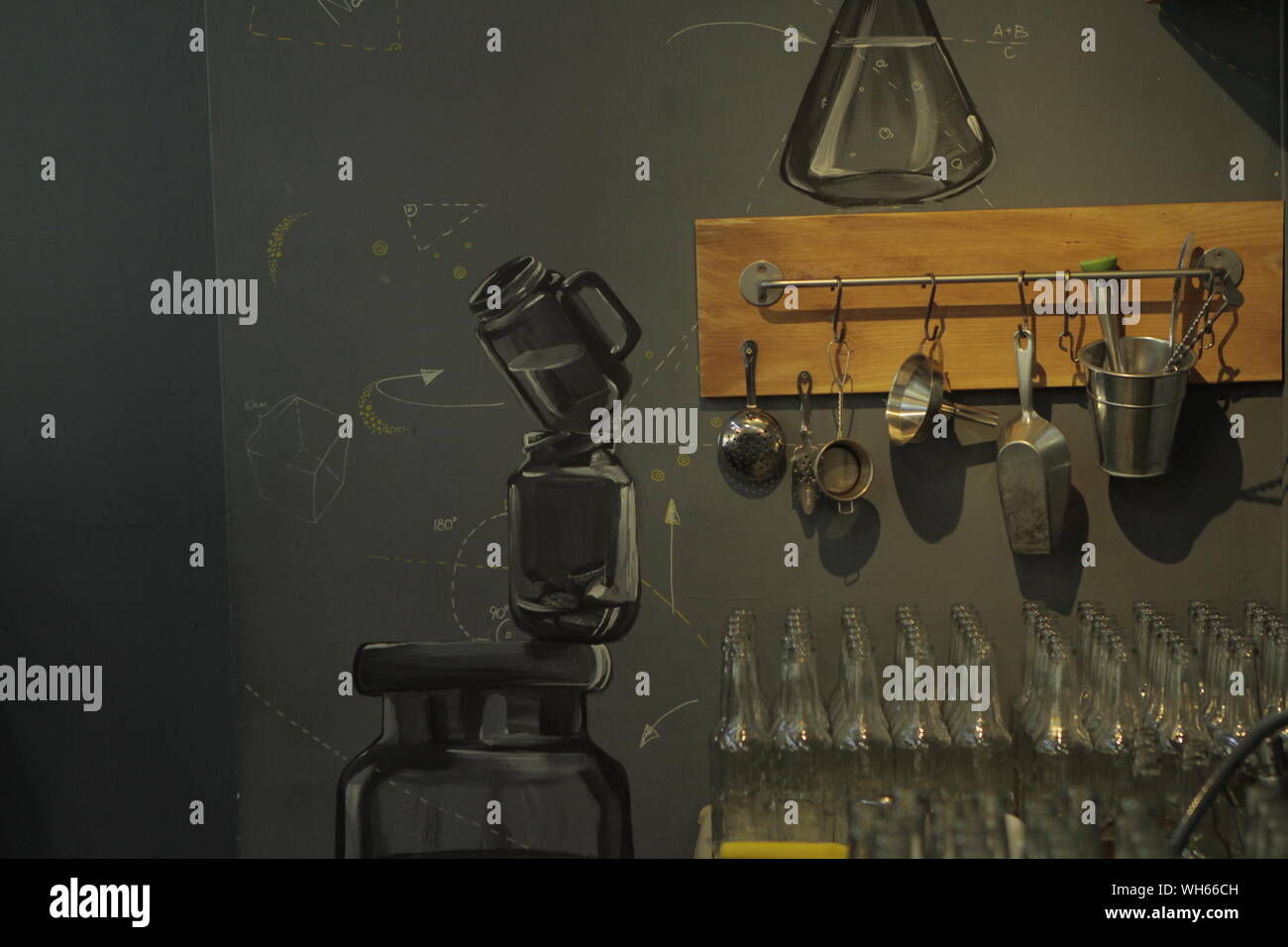 Glass Bottles And Kitchen Utensils Hanging On Painted Wall Stock Photo